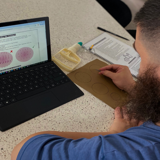 Hijama Certificate Course practical training showing person practicing cup placement and incision on synthetic skin with laptop and manual